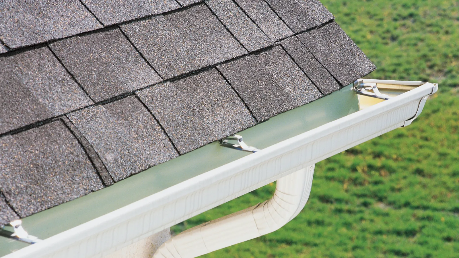 Shingle roof corner with a gutter and downspout