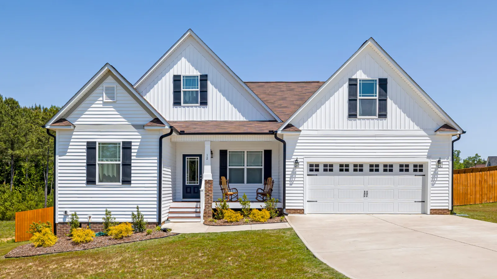 Attached two-car garage on a white home under a brown shingle roof