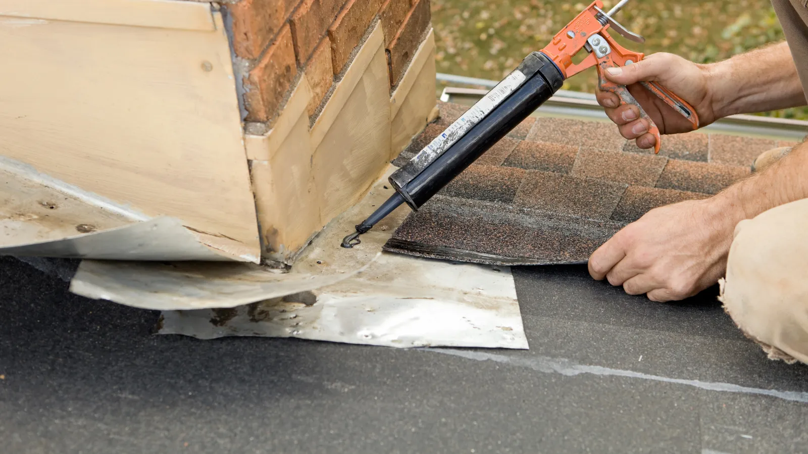 Caulking gun used by a roofer to seal chimney flashing