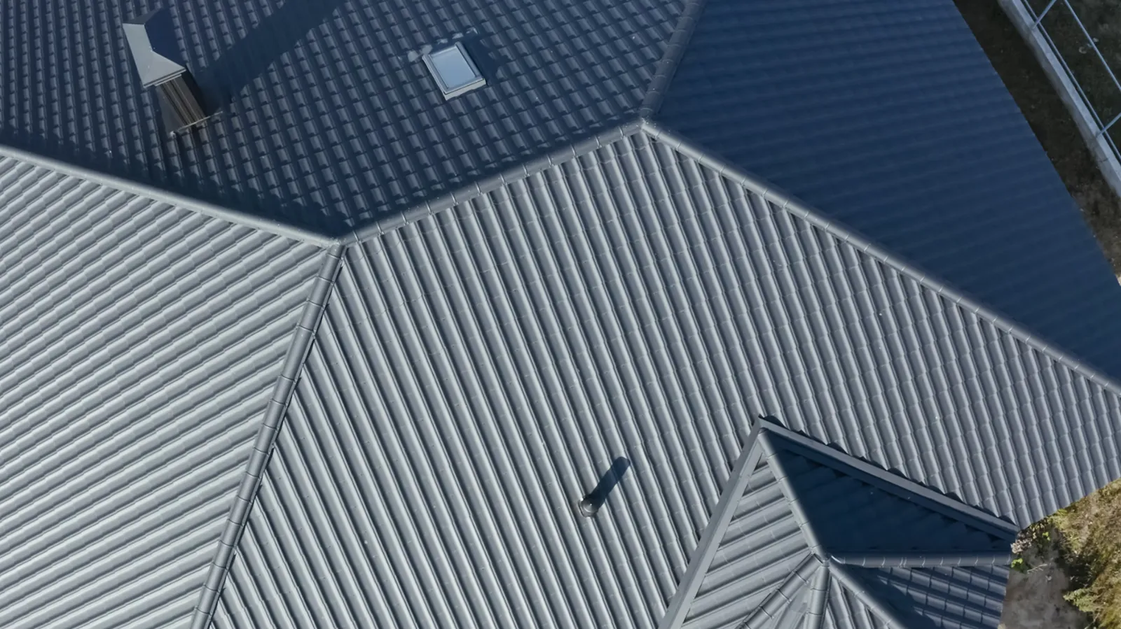 Gray metal roof sections with a skylight and chimney seen from above